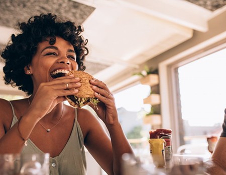 Woman happily eating a sandwich at a restaurant