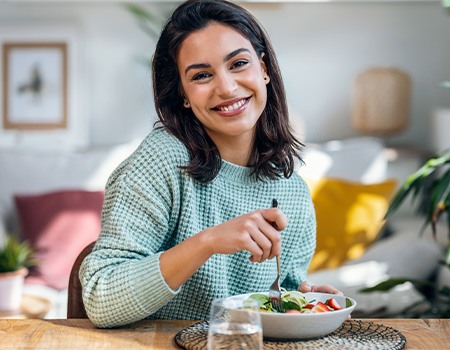 Woman smiling while eating healthy lunch