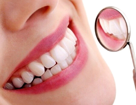 closeup of womans teeth in dental mirror