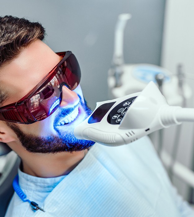 a smiling man getting his teeth whitened